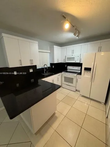 a kitchen with granite countertop white cabinets and black appliances