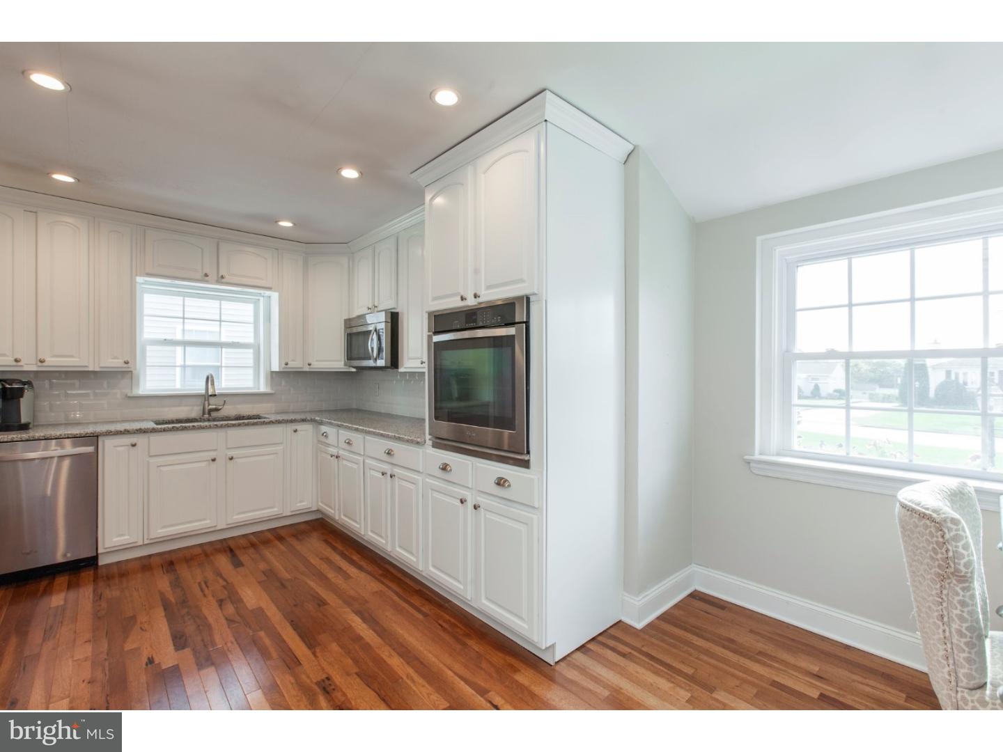 1238 Dill Road Havertown, PA 19083 - Photo 5 of 23 a kitchen with granite countertop a stove top oven a sink dishwasher and white cabinets with wooden floor