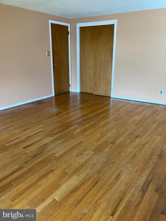 a view of an empty room with wooden floor and closet