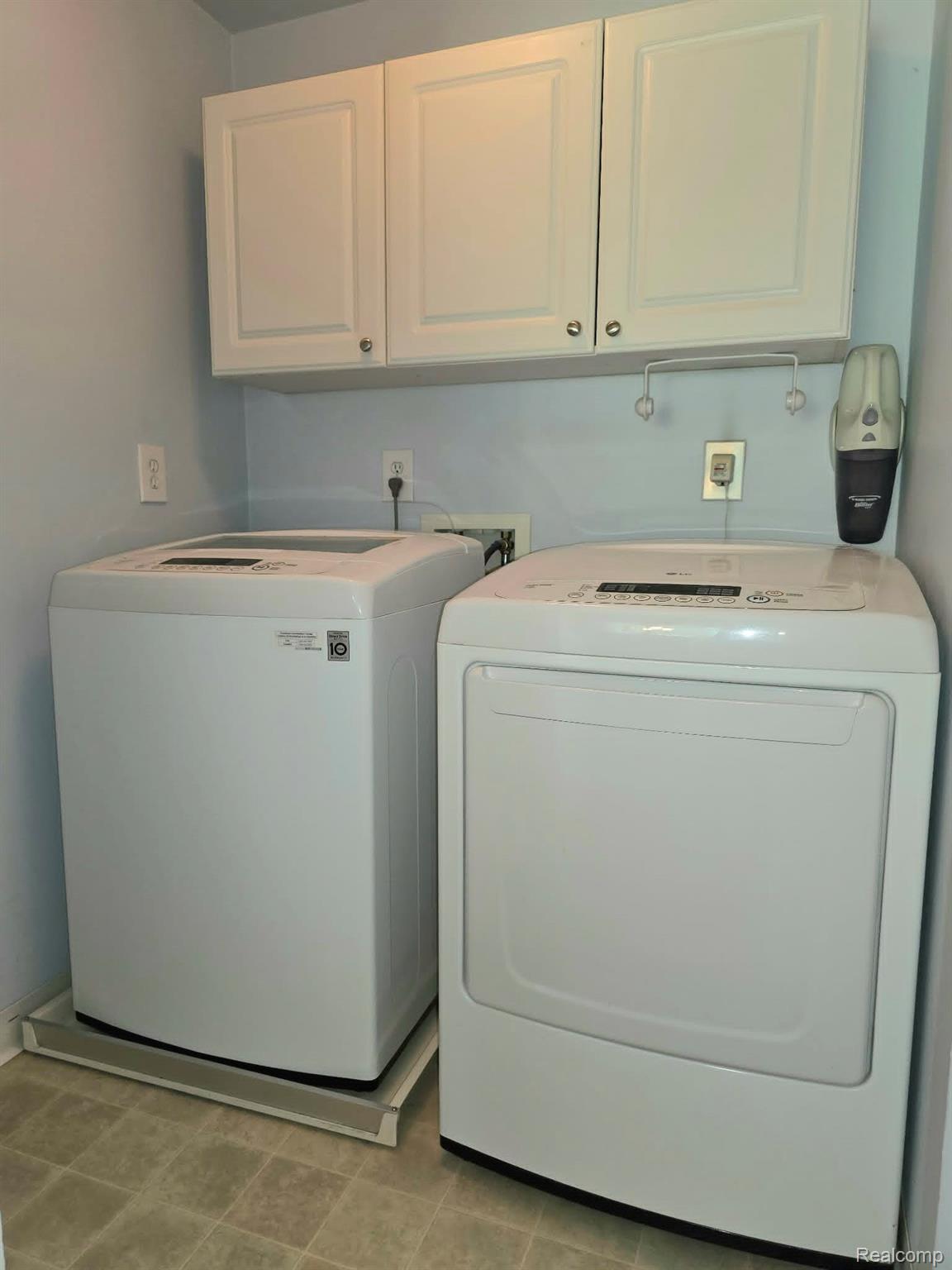 5158 Coldwater Road Columbiaville, MI 48421 - Photo 12 of 25 Laundry area featuring white cabinetry with brushed nickel hardware, light blue wall paint, and patterned floor tile