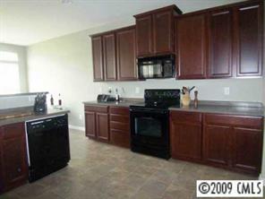712 Beille Lane Fort Mill, SC 29708 - Photo 3 of 8 a kitchen with granite countertop wooden cabinets and black appliances