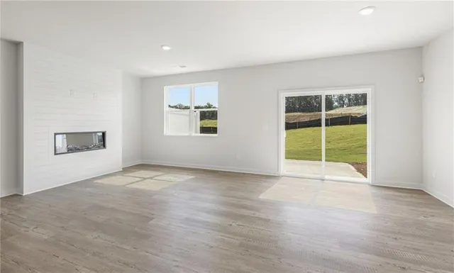 a view of an empty room with a window and wooden floor