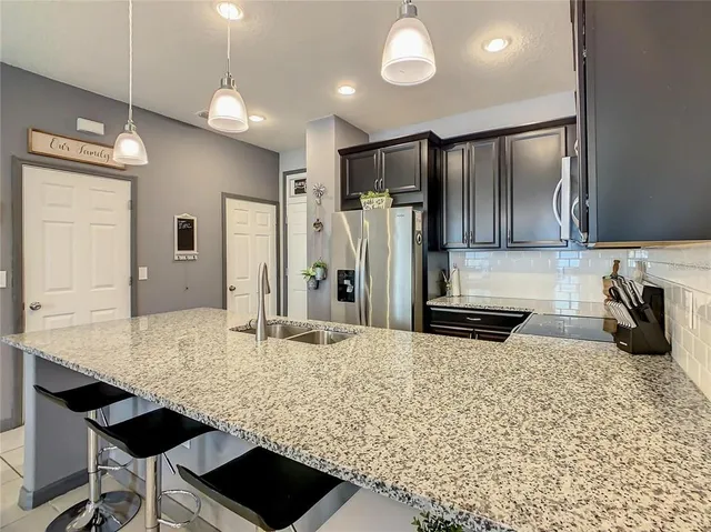 a kitchen with stainless steel appliances kitchen island granite countertop a refrigerator and a stove top oven