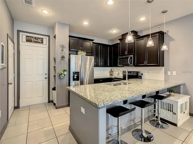 a kitchen with stainless steel appliances granite countertop a refrigerator a sink a stove top oven and cabinetry