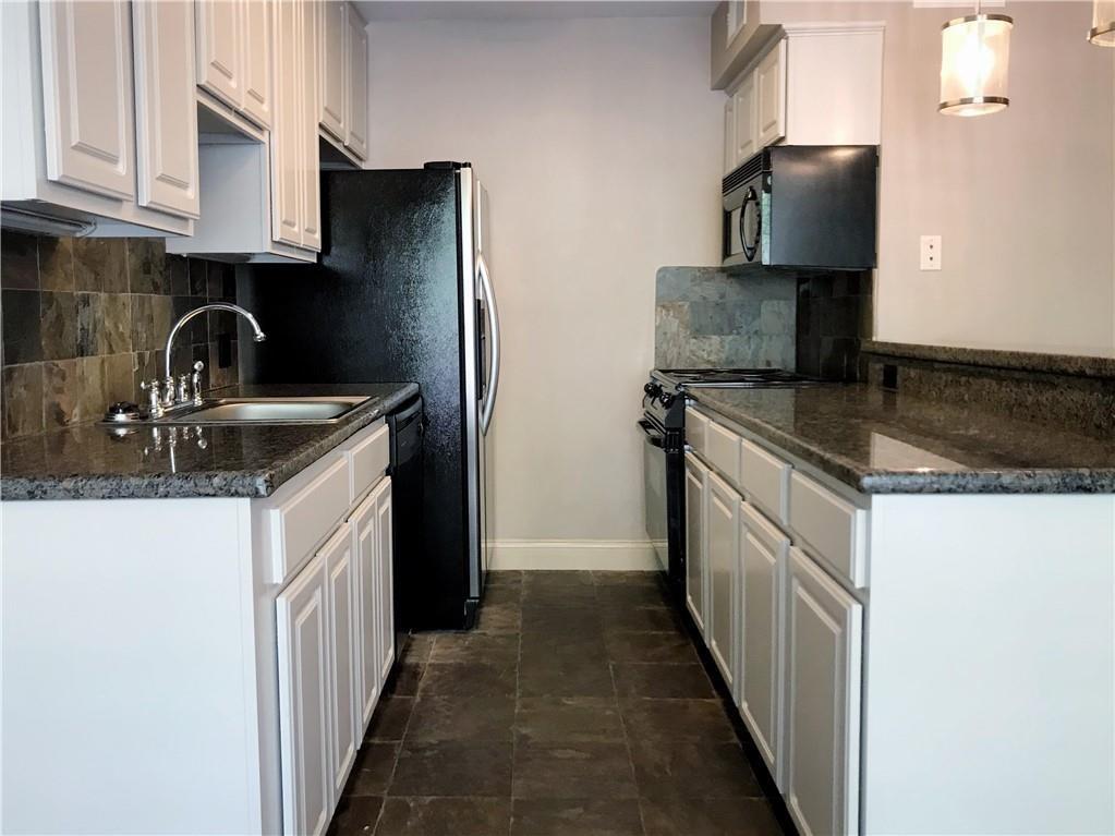 500 East Riverside Drive, Unit 154 Austin, TX 78704 - Photo 4 of 13 Kitchen with white cabinets, dark stone counters, pendant lighting, black appliances, and backsplash