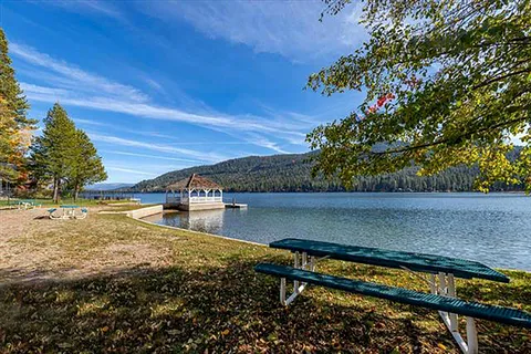 a view of a backyard with lawn chairs under an umbrella