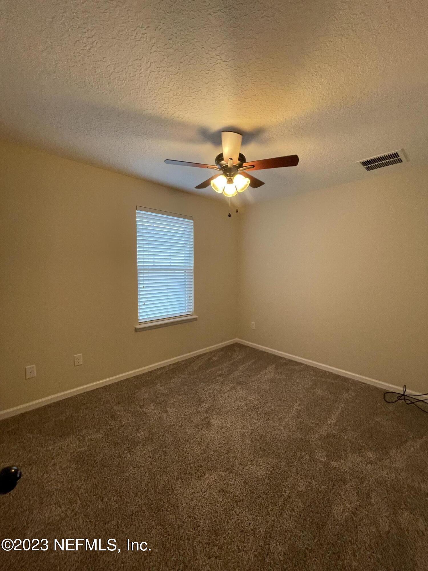41 Nelson Lane St. Johns, FL 32259 - Photo 7 of 18 an empty room with a chandelier fan and windows