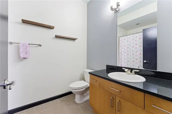 a bathroom with a granite countertop sink a toilet and a mirror