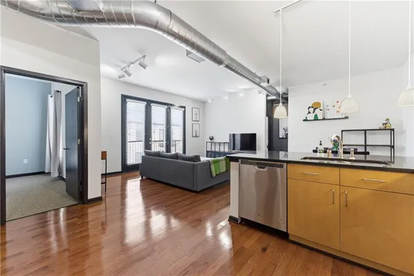 a living room with stainless steel appliances kitchen island granite countertop wooden floors and a view of living room