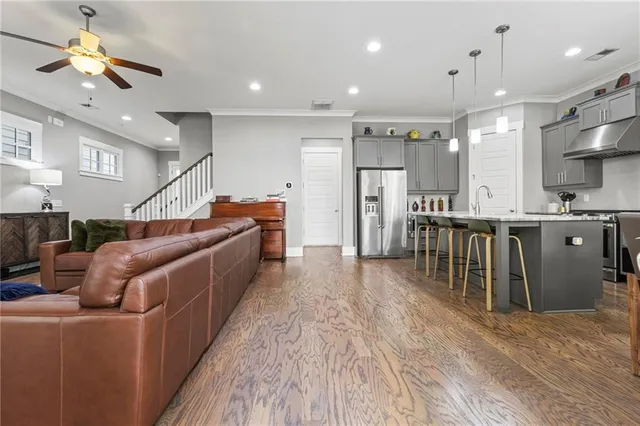 a kitchen with stainless steel appliances kitchen island granite countertop a refrigerator a stove a sink and a dining table with wooden floor