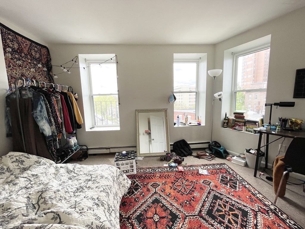 96 Hammond Street, Unit 4 Boston, MA 02120 - Photo 6 of 10 a bedroom with a bed a large window and dresser