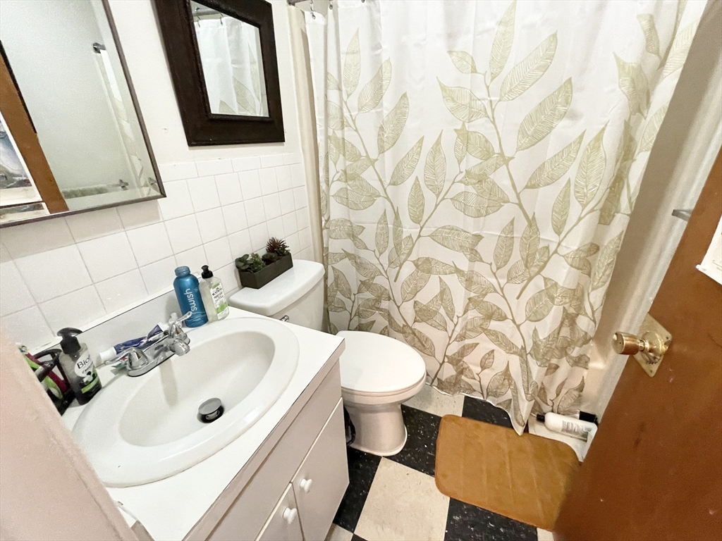 96 Hammond Street, Unit 4 Boston, MA 02120 - Photo 9 of 10 a bathroom with a sink and mirror with toilet