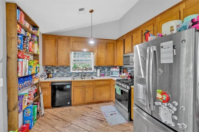 a kitchen with stainless steel appliances granite countertop a refrigerator a stove and a sink