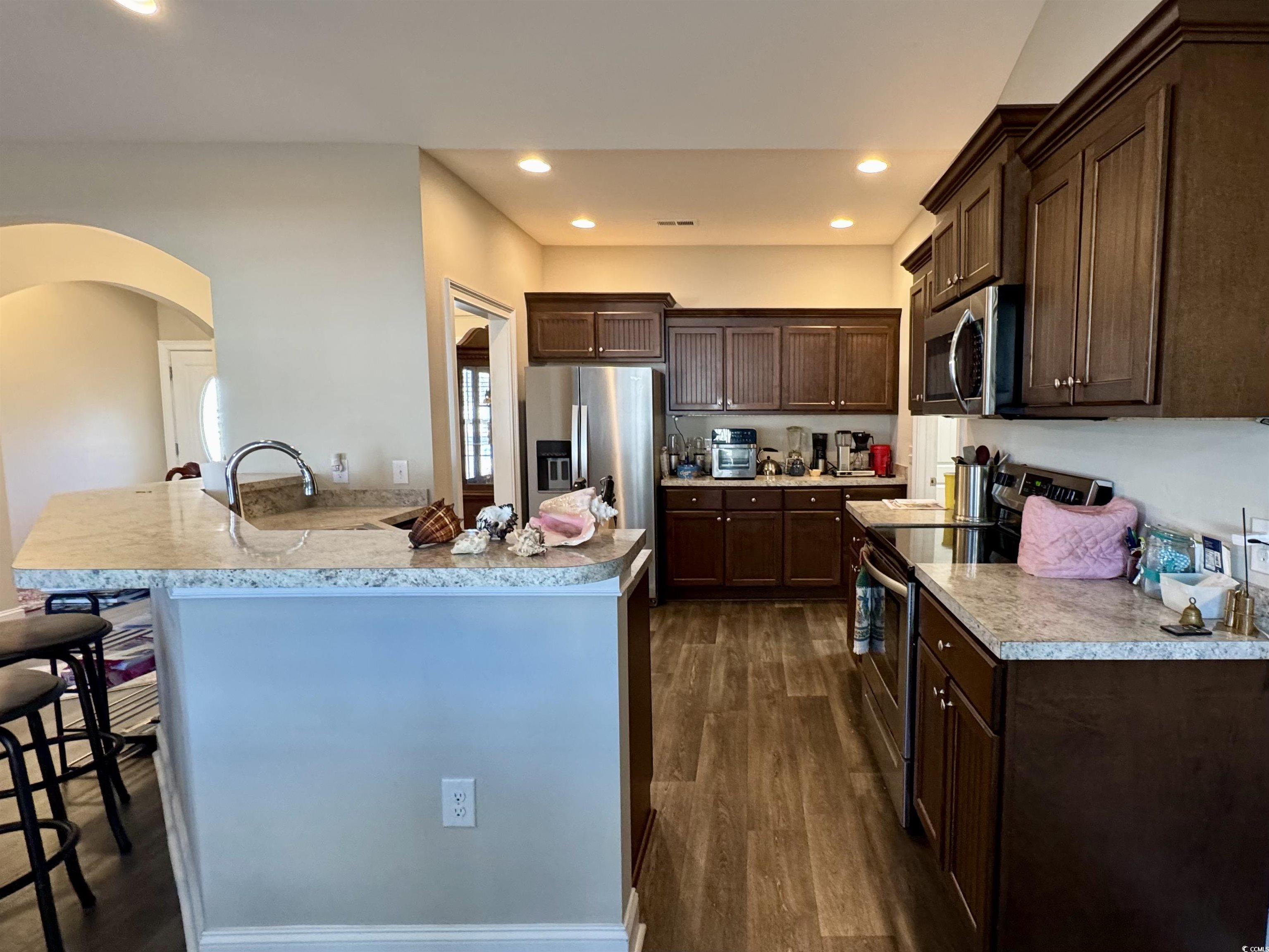 117 Baylee Circle Galivants Ferry, SC 29544 - Photo 6 of 17 Kitchen featuring appliances with stainless steel finishes, dark brown cabinetry, light countertops, arched walkways, and dark wood-style floors