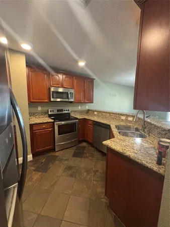 a kitchen with stainless steel appliances granite countertop a sink stove and refrigerator