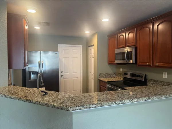 a kitchen with stainless steel appliances granite countertop wooden cabinets a granite counter tops and a stove top oven