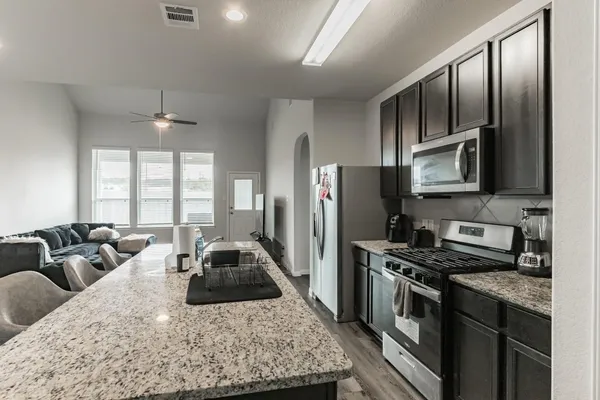 a kitchen with stainless steel appliances granite countertop a stove a sink dishwasher a refrigerator and cabinets with wooden floor