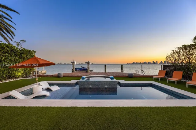a view of a swimming pool with lawn chairs and a dining table and chairs with palm trees