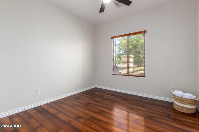 an empty room with wooden floor cabinet and windows