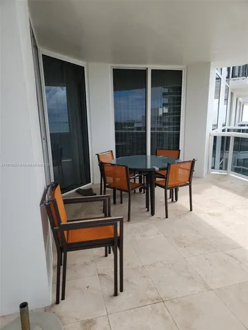 a view of a terrace with furniture and a floor to ceiling window