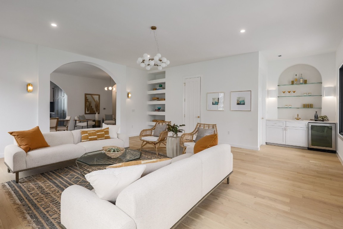 a living room with furniture kitchen view and a chandelier