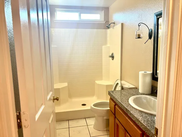 a bathroom with a granite countertop sink a toilet a mirror and shower