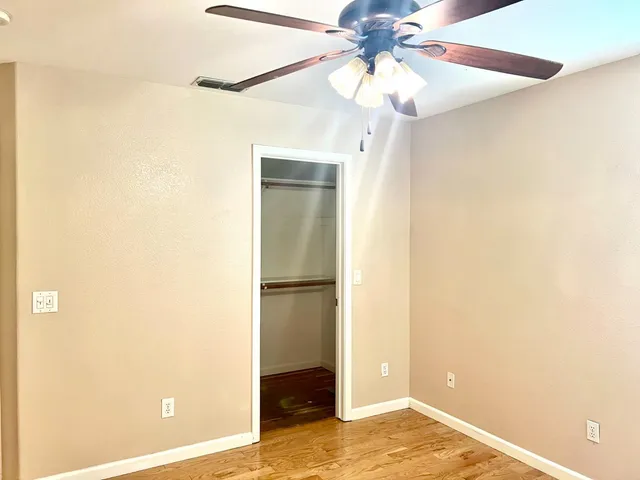 a view of a room with a ceiling fan and wooden floor