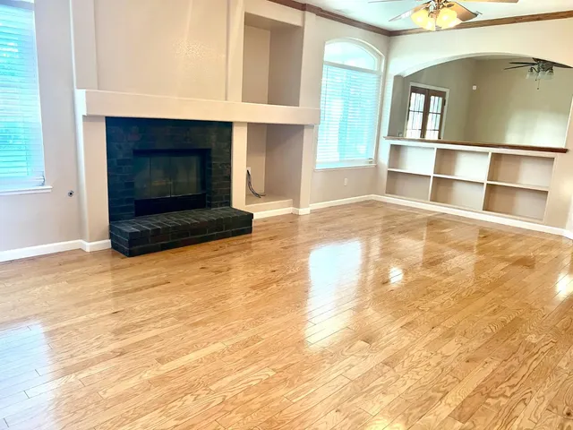 a view of an empty room with wooden floor and a fireplace