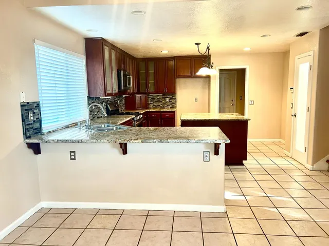 a view of kitchen with kitchen island granite countertop a sink and a stove