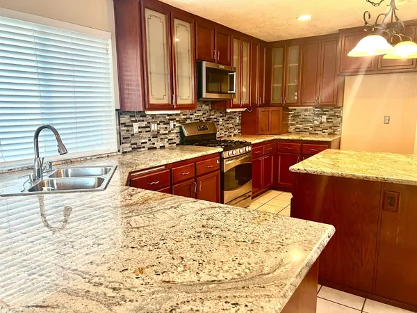 a kitchen with stainless steel appliances kitchen island granite countertop wooden cabinets a sink and dishwasher