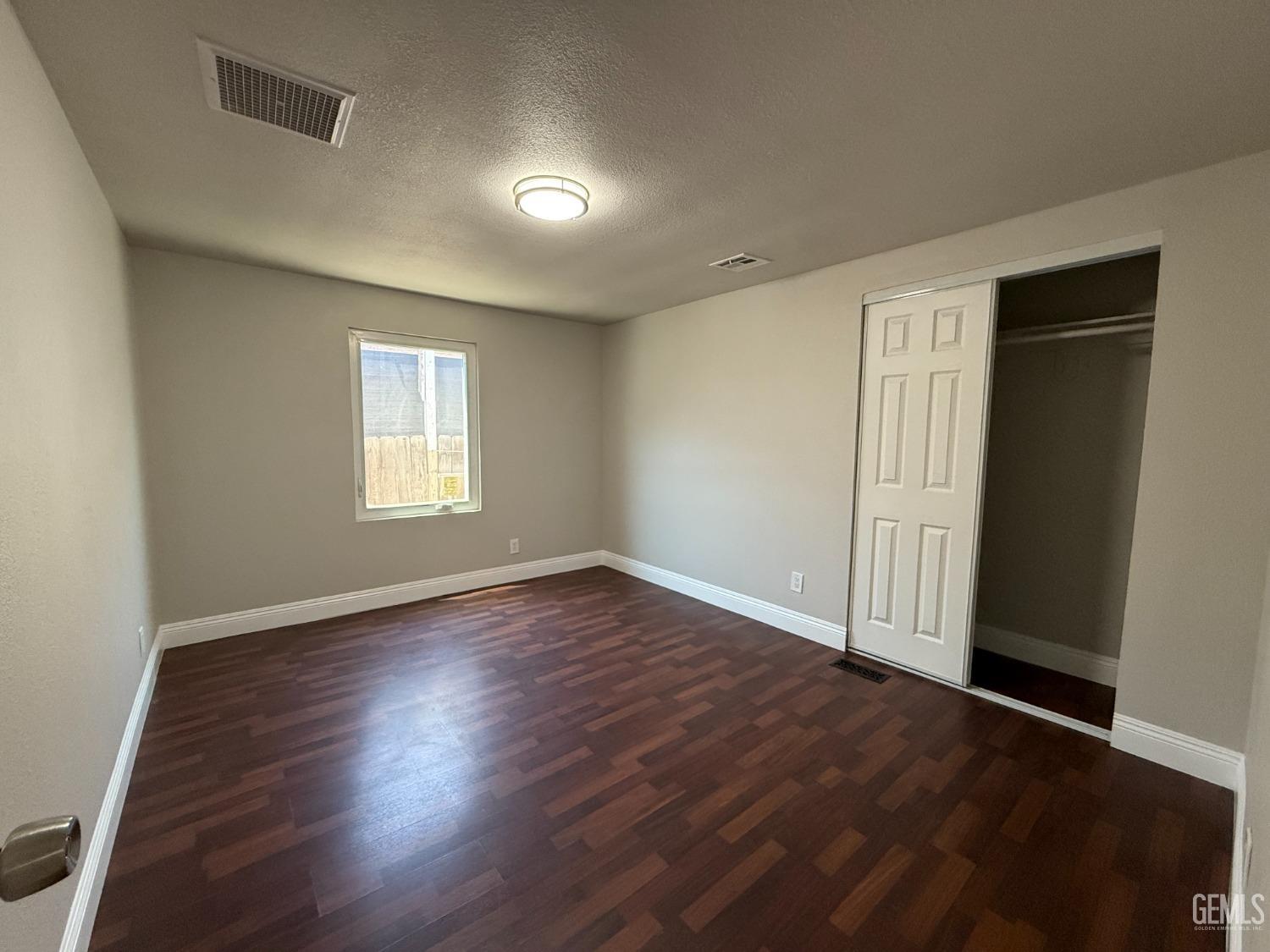 Undisclosed Address Bakersfield, CA 93307 - Photo 14 of 27 an empty room with wooden floor and windows
