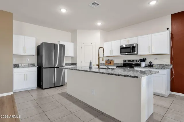 a kitchen with stainless steel appliances kitchen island granite countertop a sink and cabinets