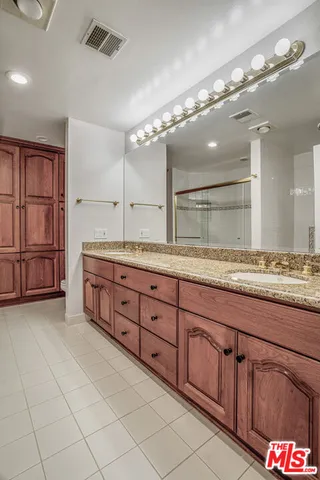a spacious bathroom with a granite countertop sink a mirror and a shower