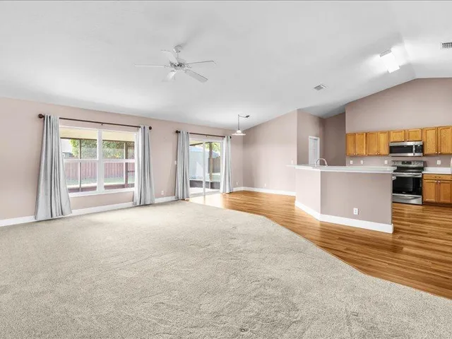 a view of a kitchen with kitchen island a ceiling fan and a rug