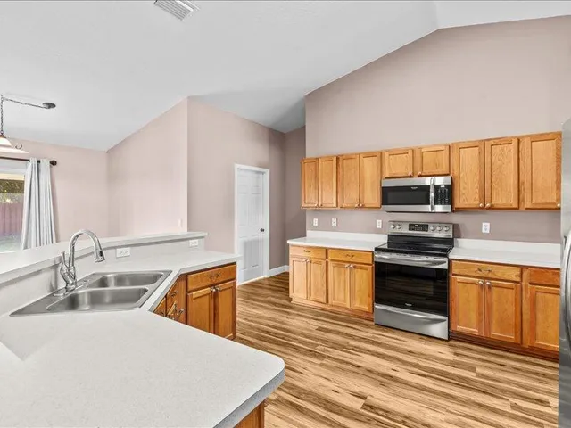 a kitchen with stainless steel appliances granite countertop a sink stove and wooden floor