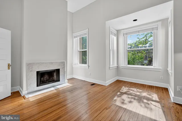 a view of an empty room with window and wooden floor