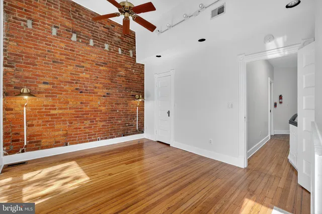 a view of an empty room with wooden floor fireplace and a window