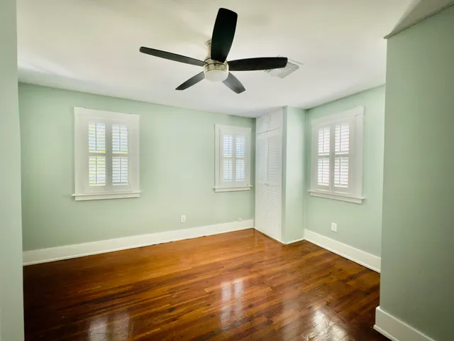 a view of empty room with wooden floor and fan
