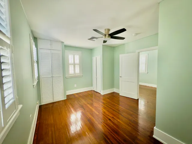 a view of empty room with wooden floor and fan