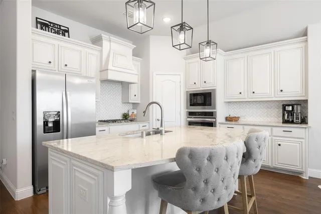 a kitchen with stainless steel appliances granite countertop a dining table chairs refrigerator and cabinets