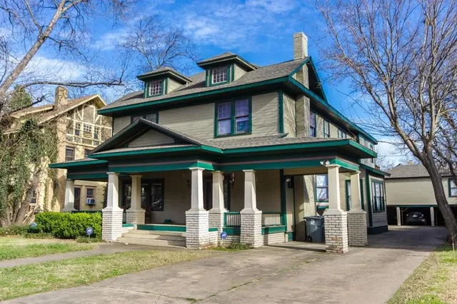 a view of a brick house with large windows and a large tree