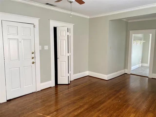 an empty room with wooden floor & closet area