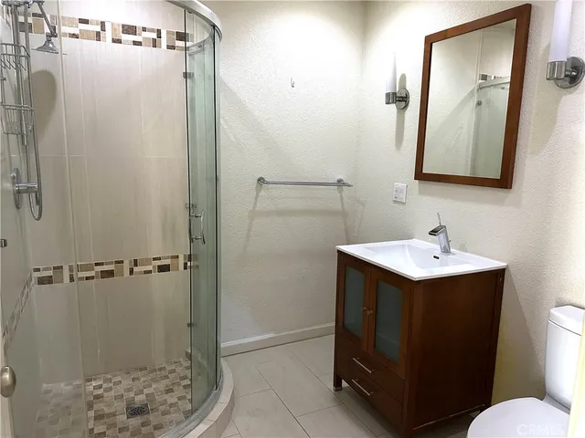 a bathroom with a sink a toilet a mirror and shower
