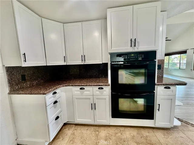 a kitchen with stainless steel appliances granite countertop white cabinets and black stove