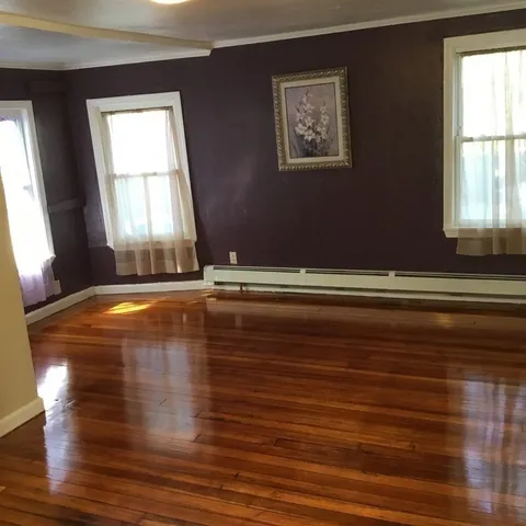 a view of empty room with wooden floor and window