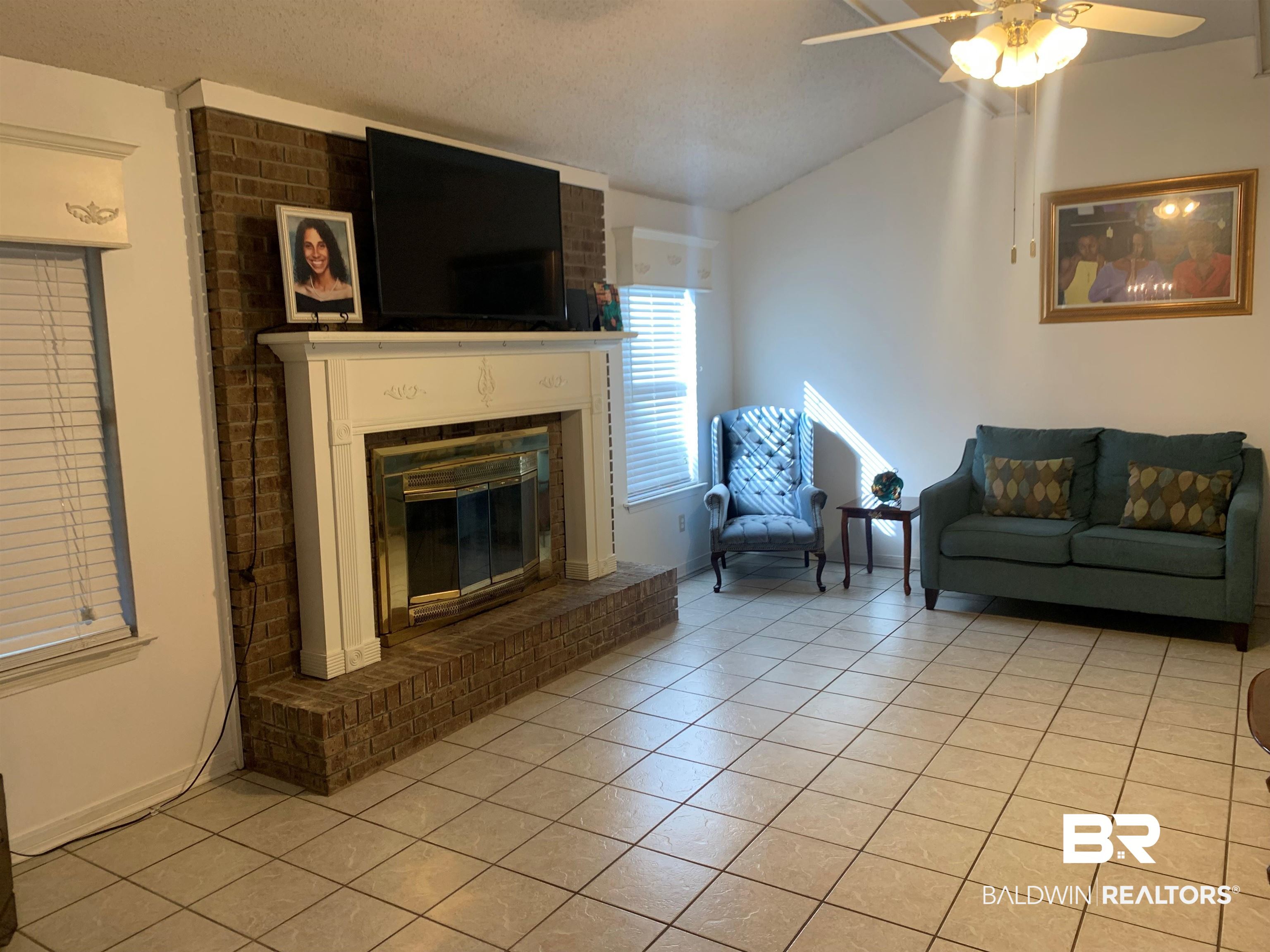 133 Dunbar Loop Daphne, AL 36526 - Photo 5 of 15 Living room with light tile patterned floors, a fireplace, a textured ceiling, ceiling fan, and vaulted ceiling