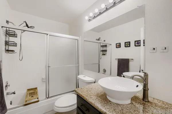 a bathroom with a granite countertop sink toilet a mirror and shower