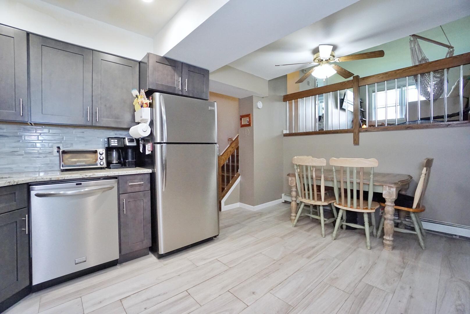 40 Racal Court, Unit B1 Staten Island, NY 10314 - Photo 3 of 16 a kitchen with stainless steel appliances granite countertop a dining table chairs and a refrigerator