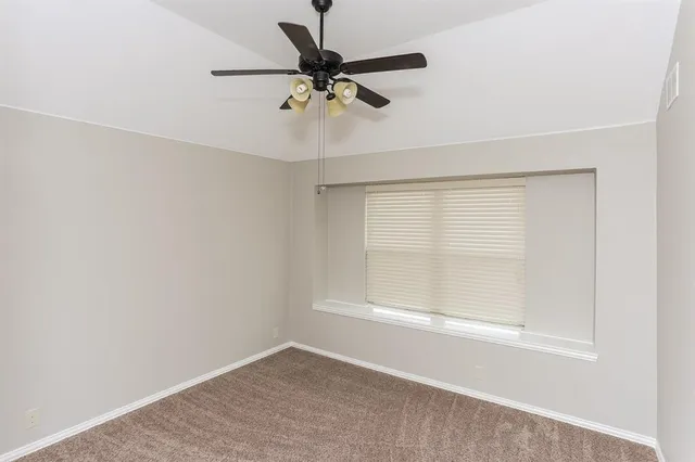 an empty room with a window and a ceiling fan