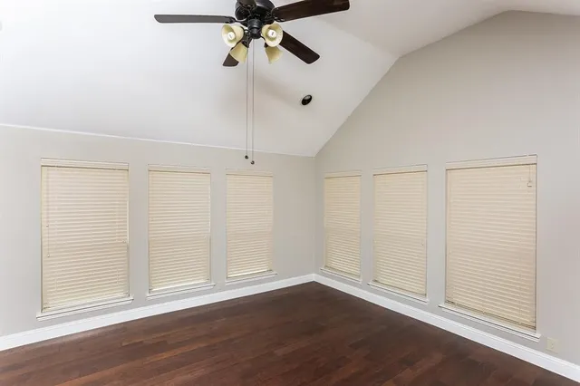an empty room with wooden floor closet and windows